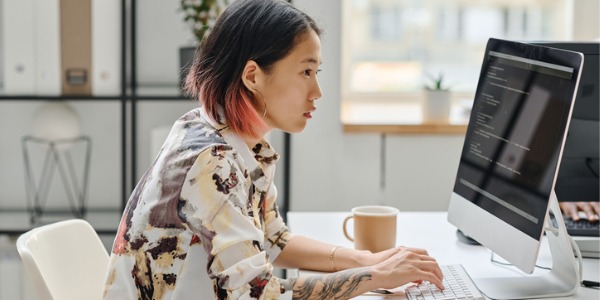 A web developer writing code on her computer.