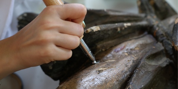A museum conservator working on the preservation of an old sculpture.