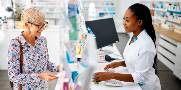 A pharmacist smiling and assisting a customer with questions related to his medication.