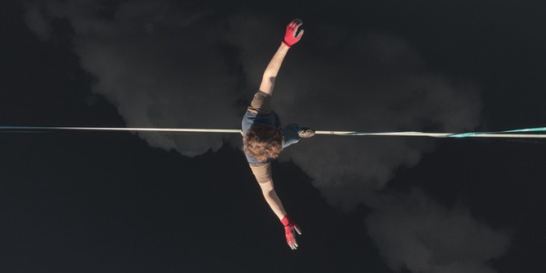 A tightrope walker balancing on a tightrope high up in the air.