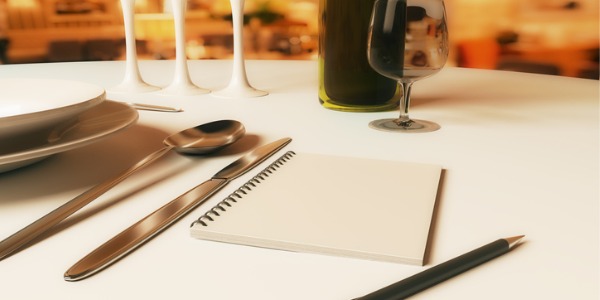 A place setting at a restaurant with a notebook beside the plate to be used by a food critic.