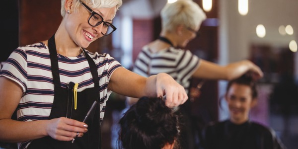 A hairdresser smiling and talking with her client.