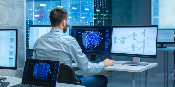 A machine learning engineer working at his desk on the computer.